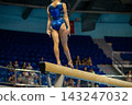 Female gymnast standing on balance beam 143247032
