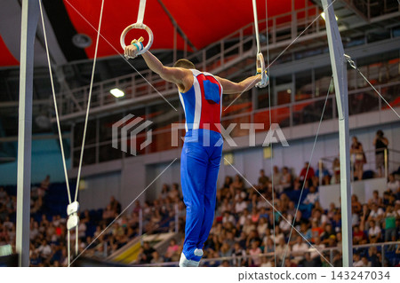 Male russian gymnast performing iron cross on still rings Male russian gymnast performing iron cross on still rings 143247034
