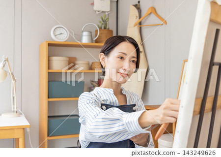 A Japanese woman painting at her easel in her studio. A Japanese woman painting at her easel in her studio. 143249626