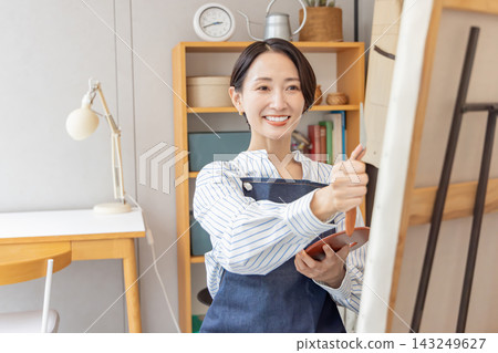 A Japanese woman painting at her easel in her studio. A Japanese woman painting at her easel in her studio. 143249627