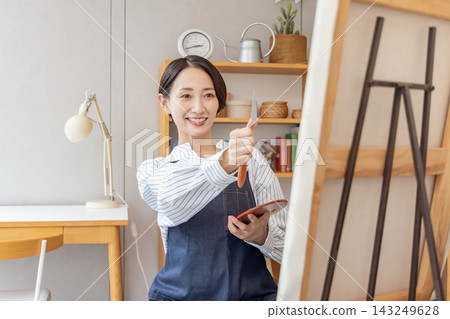 A Japanese woman painting at her easel in her studio. A Japanese woman painting at her easel in her studio. 143249628