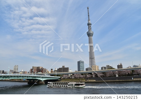 Asakusa, Tokyo, Japan: A sightseeing boat sailing down the Sumida River, with the Tokyo Skytree in full bloom, cherry blossoms in full bloom, and a beautiful blue sky. Asakusa, Tokyo, Japan: A sightseeing boat sailing down the Sumida River, with the Tokyo Skytree in full bloom, cherry blossoms in full bloom, and a beautiful blue sky. 143250215