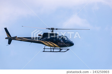 Helicopter flying through a clear blue sky with its rotor blades in motion with copy space Helicopter flying through a clear blue sky with its rotor blades in motion with copy space 143250903