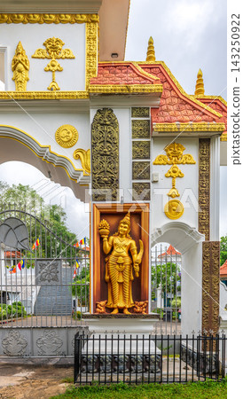 Buddhist temple entrance featuring golden religious sculptures, decorative details, and red tiled roofs in Weligama, Sri Lanka Buddhist temple entrance featuring golden religious sculptures, decorative details, and red tiled roofs in Weligama, Sri Lanka 143250922