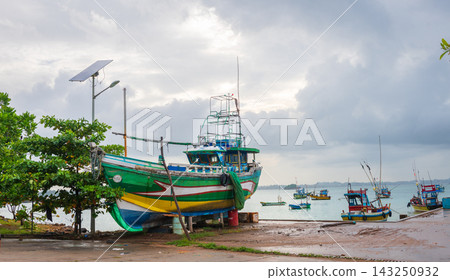 An old colorful fishing boat sits on shore at Weligama Harbour in Sri Lanka, surrounded by traditional fishing vessels floating in the calm coastal waters An old colorful fishing boat sits on shore at Weligama Harbour in Sri Lanka, surrounded by traditional fishing vessels floating in the calm coastal waters 143250932