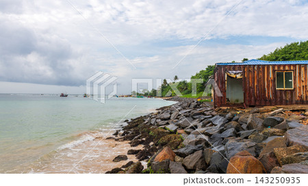 A weathered container shelter on a rocky shoreline beside calm tropical waters at weligama harbour, sri lanka. A weathered container shelter on a rocky shoreline beside calm tropical waters at weligama harbour, sri lanka. 143250935