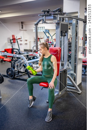 Young woman having break after sport training and drinking water from green glass bottle. Self care, life balance and healthy lifestyle concept. Young woman having break after sport training and drinking water from green glass bottle. Self care, life balance and healthy lifestyle concept. 143251355
