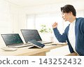 A man in his 20s makes a triumphant gesture while looking at stock charts at home. 143252432