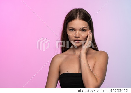 Woman applying translucent under eye patches for a cosmetic skin treatment, embodying self-care and a healthy glow Woman applying translucent under eye patches for a cosmetic skin treatment, embodying self-care and a healthy glow 143253422