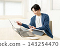 A young man working using multiple laptops and a tablet. 143254470