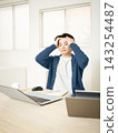 A young man sits in front of his computer, holding his head in frustration. 143254487