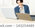 A young man using a computer or tablet lined up on his desk. 143254489
