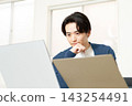 A man working at his desk, staring at his computer screen. 143254491