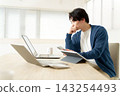 A young man working using multiple laptops and a tablet. 143254493