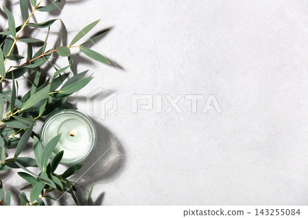 Eucalyptus Leaves and Scented Candle on Minimal Light Background Eucalyptus Leaves and Scented Candle on Minimal Light Background 143255084