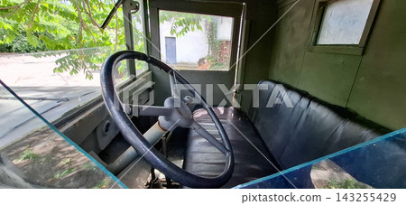 Vintage ZIS-5 military truck with a wooden cab. Interior view of a vintage retro military truck cabin with steering wheel and leather seat. Vintage ZIS-5 military truck with a wooden cab. Interior view of a vintage retro military truck cabin with steering wheel and leather seat. 143255429