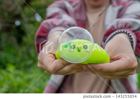 Close up of female hands showing a green cute caterpillar squishy toy with a big transparent bubble. Sensory integration and focus development concept Close up of female hands showing a green cute caterpillar squishy toy with a big transparent bubble. Sensory integration and focus development concept 143255854