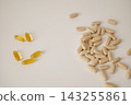 Yellow transparent capsules beside a pile of beige elongated capsules on a light surface. Capsule type comparison and supplement selection concept 143255861