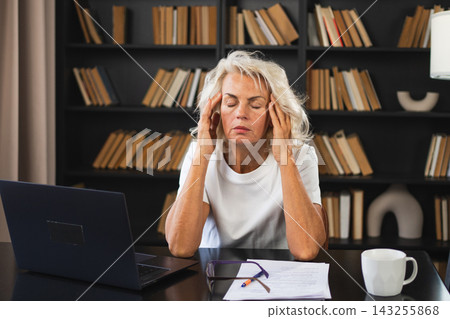 Headache pain. Middle aged woman touching temples experiencing stress. Mature old lady tired of work feeling headache sick rubbing temples forehead. Long laptop usage computer vision office syndrome Headache pain. Middle aged woman touching temples experiencing stress. Mature old lady tired of work feeling headache sick rubbing temples forehead. Long laptop usage computer vision office syndrome 143255868