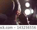 Makeup Artist Applying Finishing Touches To Model Backstage In Dressing Room With Vanity Lights 143256556