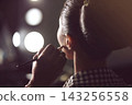 Makeup Artist Applying Finishing Touches To Model Backstage In Dressing Room With Vanity Lights 143256558