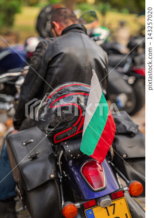 Motorcycle Helmet and Bulgarian Flag on Touring Bike behind unrecognizable motorcyclist back, outdoor city motorcycle gathering. Travel, community and national identity concept Motorcycle Helmet and Bulgarian Flag on Touring Bike behind unrecognizable motorcyclist back, outdoor city motorcycle gathering. Travel, community and national identity concept 143257020