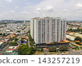 An elevated cityscape shows dense residential development with high-rise apartment buildings displaying numerous Vietnamese flags beneath a cloudy sky. 143257219
