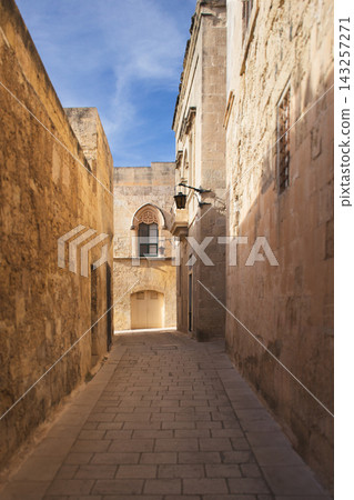 Medieval Mdina street with Gothic arched window and limestone architecture 143257271