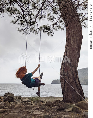 a girl swings on a swing on a tree near a lake a girl swings on a swing on a tree near a lake 143257318