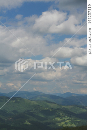 Scenic panoramic view of rolling green mountain ridges under a blue sky with white clouds Scenic panoramic view of rolling green mountain ridges under a blue sky with white clouds 143257319