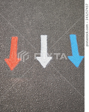 Three multicolored arrows on the gray asphalt: blue, white, and red. Directional signs. Three multicolored arrows on the gray asphalt: blue, white, and red. Directional signs. 143257437