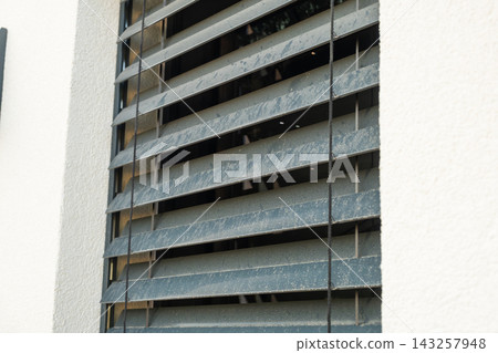 Window shutters made of durable materials are installed on the exterior of a modern residential building. The shutters allow for ventilation while maintaining privacy and aesthetics. Window shutters made of durable materials are installed on the exterior of a modern residential building. The shutters allow for ventilation while maintaining privacy and aesthetics. 143257948