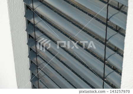 Adjustable aluminum blinds positioned within a window frame, offering customizable light filtration. The sleek design features horizontal slats with a muted gray finish, enhancing the modern aesthetic Adjustable aluminum blinds positioned within a window frame, offering customizable light filtration. The sleek design features horizontal slats with a muted gray finish, enhancing the modern aesthetic 143257970