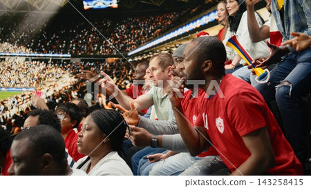 Tense sports fans checking online betting odds and cash out options on smartphone, live football match in the stadium stands. Passionate supporters tracking risky wagers on betting apps. Tense sports fans checking online betting odds and cash out options on smartphone, live football match in the stadium stands. Passionate supporters tracking risky wagers on betting apps. 143258415