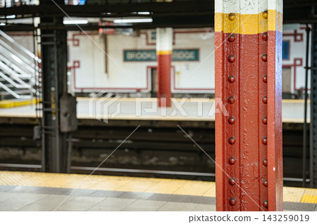 Red steel support column on the Brooklyn Bridge subway station platform in New York City. Underground tracks and tiled wall are visible across the rails. Red steel support column on the Brooklyn Bridge subway station platform in New York City. Underground tracks and tiled wall are visible across the rails. 143259019