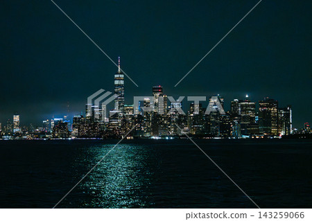 New York City skyline at night with illuminated Manhattan skyscrapers and the iconic One World Trade Center rising above downtown. Bright city lights reflect beautifully on the dark Hudson River New York City skyline at night with illuminated Manhattan skyscrapers and the iconic One World Trade Center rising above downtown. Bright city lights reflect beautifully on the dark Hudson River 143259066