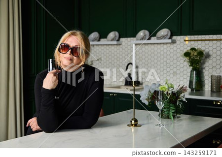 White woman stylist playfully toying with sunglasses and champagne White woman stylist playfully toying with sunglasses and champagne 143259171
