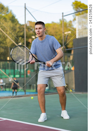 Young man playing tennis on court 143259626
