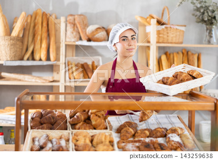 Young woman seller puts croissants in showcase Young woman seller puts croissants in showcase 143259638
