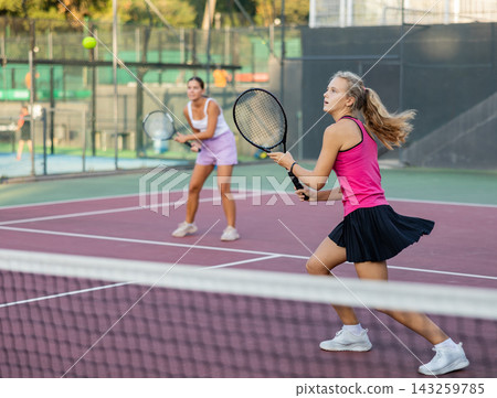 Sports active woman during friendly doubles couple match. Two women playing together tennis Sports active woman during friendly doubles couple match. Two women playing together tennis 143259785