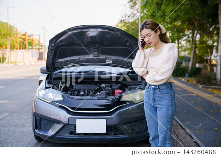 Asian woman calling roadside assistance near broken down car on street Asian woman calling roadside assistance near broken down car on street 143260488