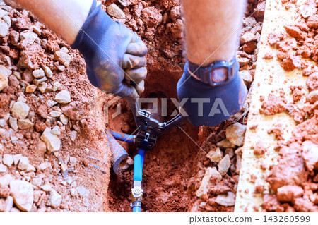 Hands worker are working on water line repair while surrounded by dirt rocks. Hands worker are working on water line repair while surrounded by dirt rocks. 143260599