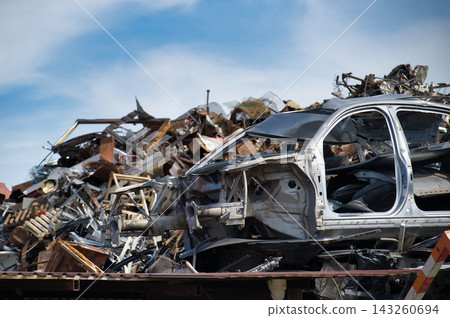 Scrapyard With Wrecked Car Frames, Piles of Scrap Metal and Industrial Salvage Under Blue Sky Scrapyard With Wrecked Car Frames, Piles of Scrap Metal and Industrial Salvage Under Blue Sky 143260694