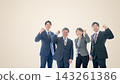 A business team of four (two men and two women) making a victory pose, smiling, against a beige background, with a margin on the left. 143261386