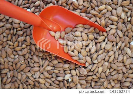 Almonds in a wooden bowl with a red scoop on a kitchen table Almonds in a wooden bowl with a red scoop on a kitchen table 143262724