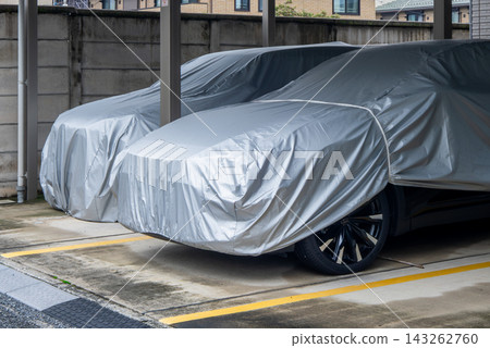 兩輛停放的汽車被銀色車罩遮住。 兩輛停放的汽車被銀色車罩遮住。 143262760