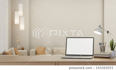 Laptop with blank screen mockup on wooden desk with lamp, pencils, books and a living room view. 143263055