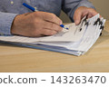 Business Professional Filling Out Paperwork at Desk 143263470