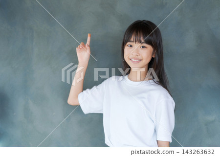 一名小學生女孩指著什麼(灰色背景) 一名小學生女孩指著什麼(灰色背景) 143263632