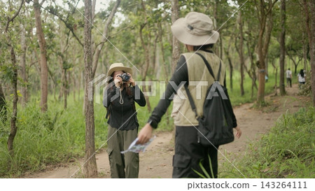Asian female traveler taking photo of her friend with camera while hiking in forest. Asian female traveler taking photo of her friend with camera while hiking in forest. 143264111